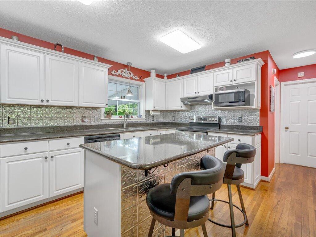 3475 Blue Knob Road Martinsville, VA 24112 - Photo 16 of 80 a kitchen with kitchen island a stove a sink and white cabinets with wooden floor