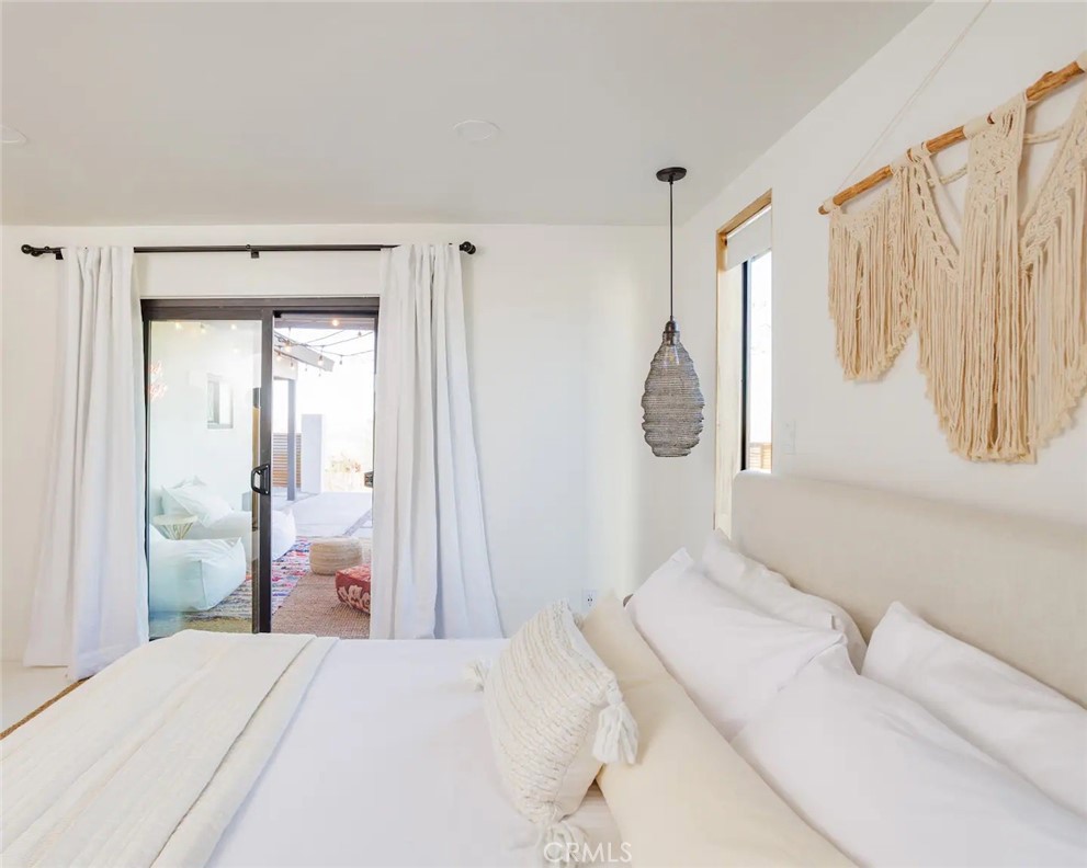 6979 White Feather Road Joshua Tree, CA 92252 - Photo 35 of 44 a bedroom with a bed a mirror and a window