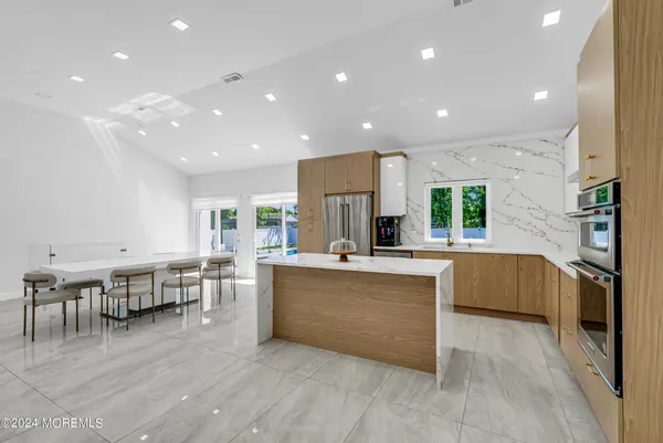 a kitchen with stainless steel appliances kitchen island granite countertop a table chairs and a refrigerator