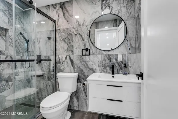 a bathroom with a sink a mirror a toilet and a shower