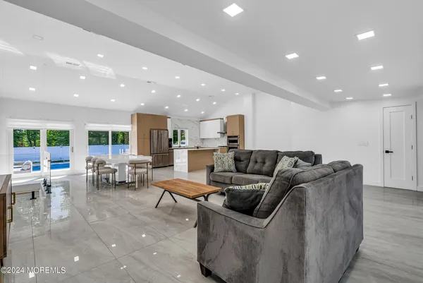 a living room with furniture large window and kitchen view
