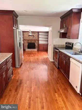 a kitchen with stainless steel appliances granite countertop a hardwood floor sink stove and granite counter top
