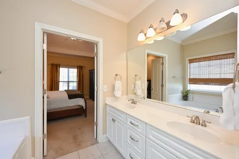 a en suite bathroom with a double vanity sink large mirror and next to a window
