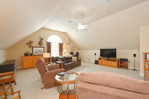 a living room with furniture a flat screen tv and a chandelier