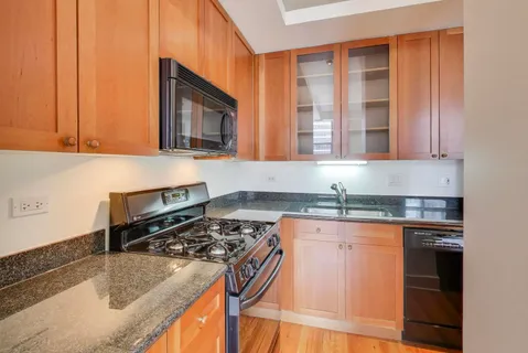 a kitchen with granite countertop a sink stove and cabinets