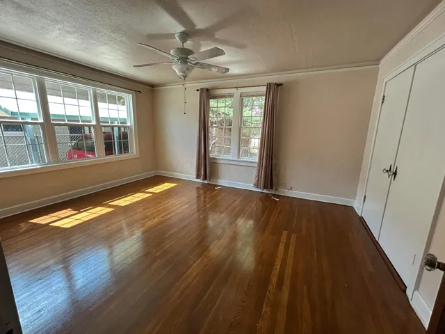 a view of an empty room with wooden floor and a window
