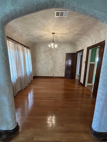 a view of an empty room with wooden floor and staircase