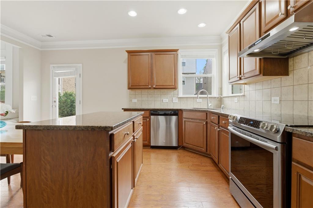 2572 Larson Creek Way Northwest Duluth, GA 30097 - Photo 23 of 50 a kitchen with stainless steel appliances granite countertop a sink a stove a refrigerator cabinets and a window