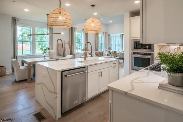 a kitchen that has a lot of white cabinets and stainless steel appliances