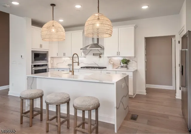 a kitchen with kitchen island stainless steel appliances a table chairs sink and stove top oven
