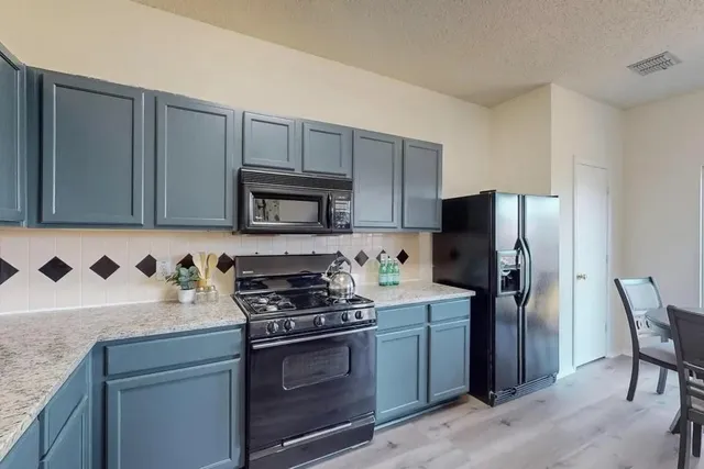 a kitchen with stainless steel appliances granite countertop a refrigerator stove and microwave