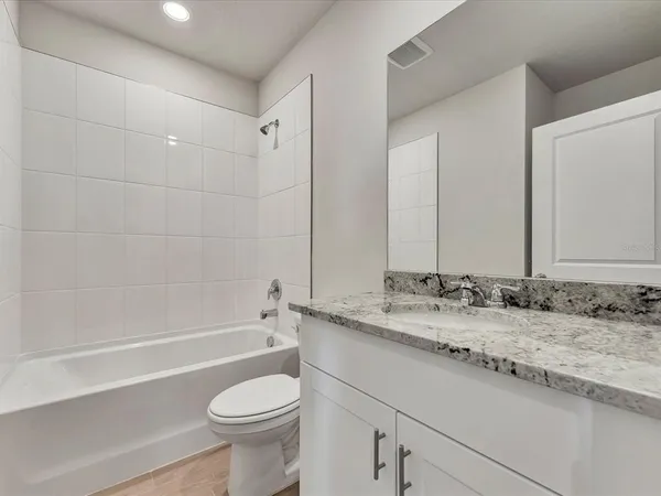 a bathroom with a granite countertop toilet sink and mirror