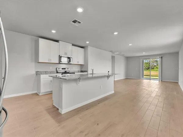 a kitchen with stainless steel appliances granite countertop a stove a sink and a refrigerator with white cabinets