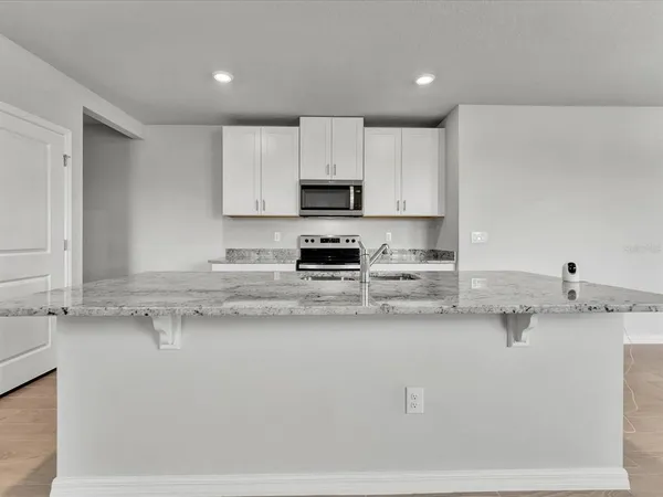 a white kitchen with granite countertop white cabinets and a stainless steel appliances