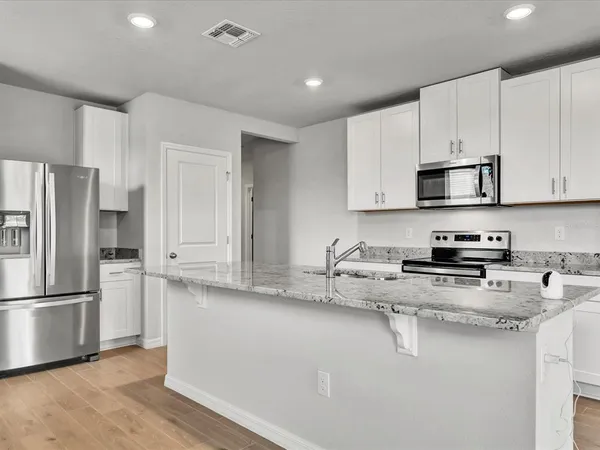a kitchen with stainless steel appliances granite countertop a refrigerator sink and white cabinets