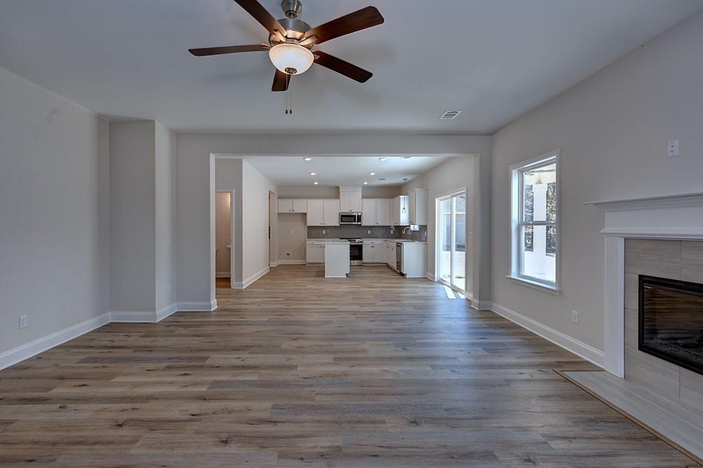 8701 McKee Road Upatoi, GA 31829 - Photo 7 of 35 a view of an empty room and kitchen view with wooden floor a ceiling fan