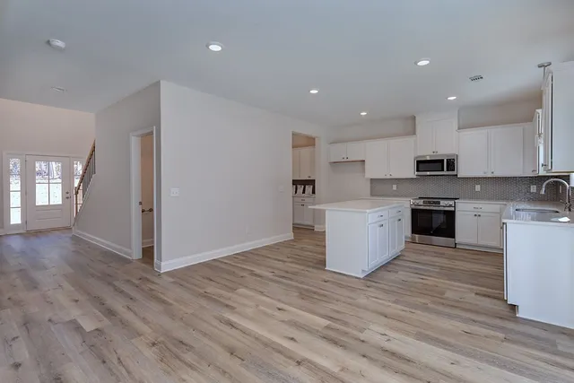 a kitchen with a sink a stove a refrigerator and white cabinets