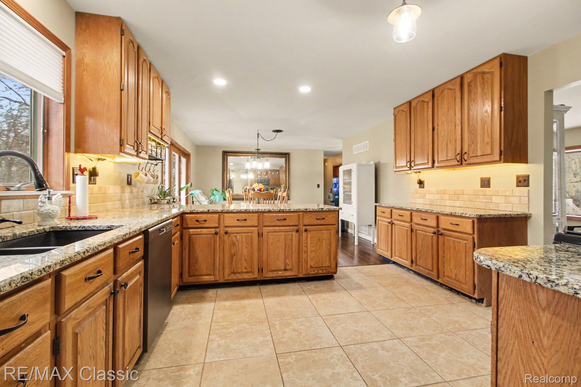 9800 Moon Road Saline, MI 48176 - Photo 8 of 38 Kitchen with backsplash, decorative light fixtures, light granite countertops, and a peninsula