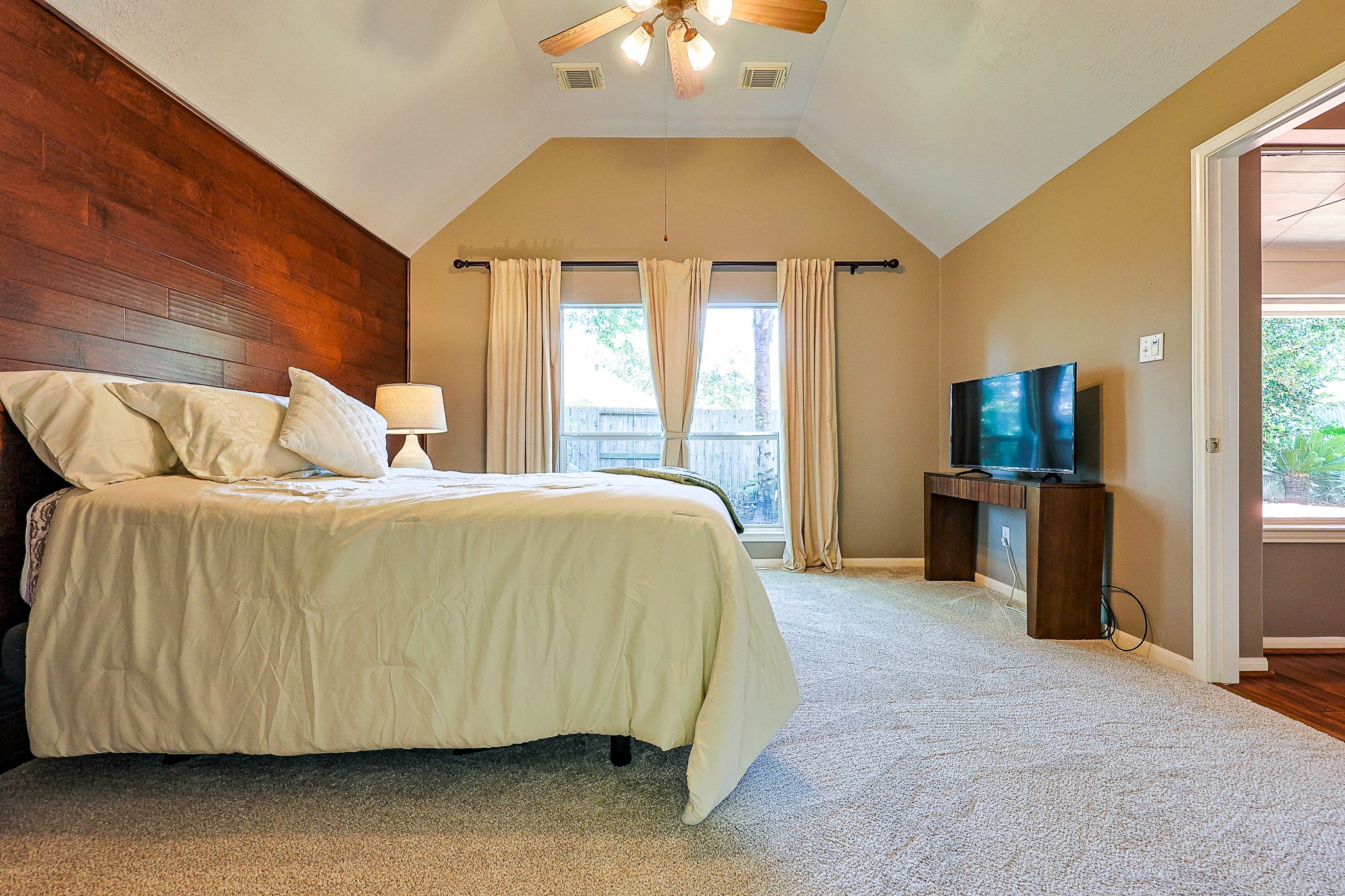 10306 Rudolph Court Missouri City, TX 77459 - Photo 17 of 34 Experience a true sanctuary in this expansive primary bedroom suite featuring a rich wood floor to ceiling accent wall that adds organic warmth and modern sophistication. Striking vaulted ceiling anchored by a large window bank overlooking the rear yard.