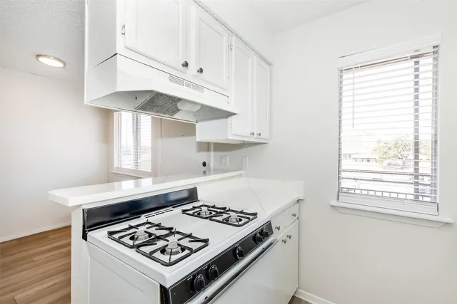 a kitchen with stainless steel appliances a stove a white cabinet and a granite counter tops
