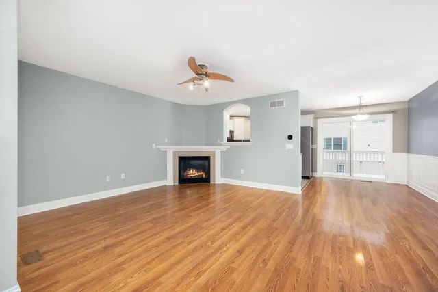 a view of an empty room with wooden floor and a fireplace