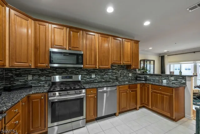 a kitchen with stainless steel appliances granite countertop wooden cabinets and a stove top oven