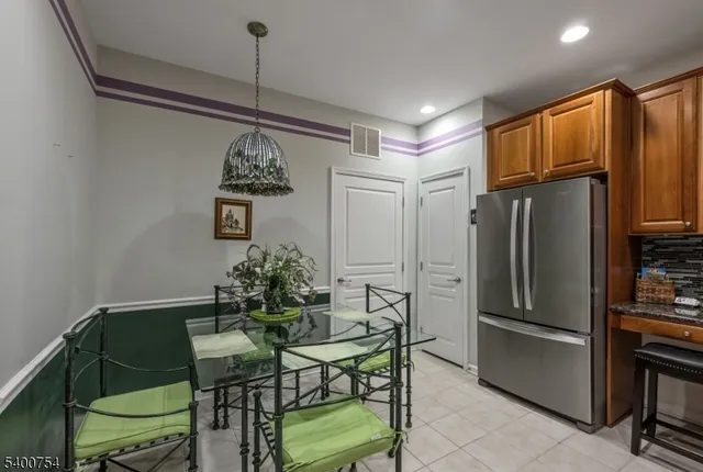 a kitchen with stainless steel appliances granite countertop a refrigerator a stove a microwave oven a dining table and chairs with wooden floor