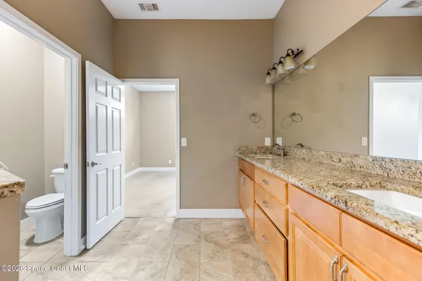 a bathroom with a granite countertop sink a toilet a mirror and shower