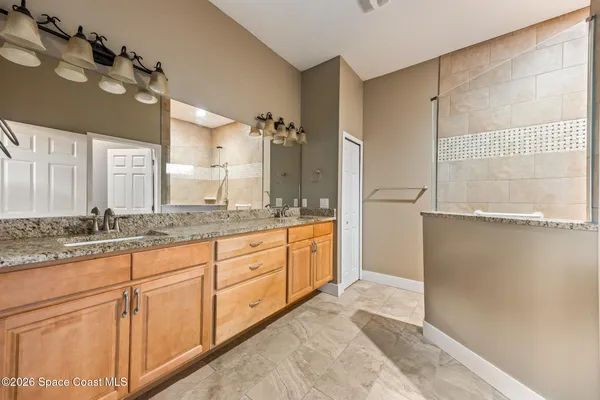 a spacious bathroom with a granite countertop sink mirror and a shower