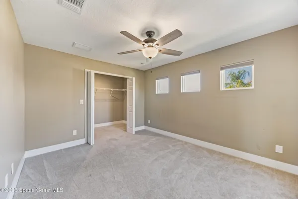 an empty room with closet and a ceiling fan