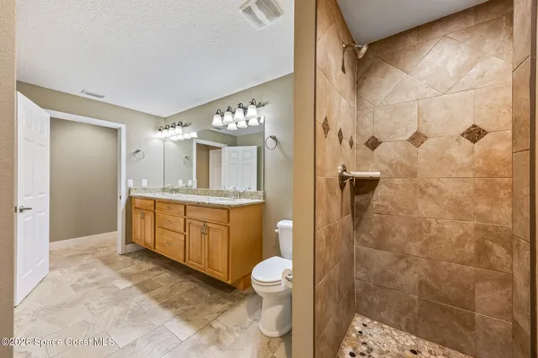 a bathroom with a granite countertop sink a toilet and shower