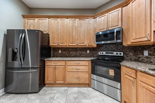 a kitchen with granite countertop a refrigerator stove and microwave