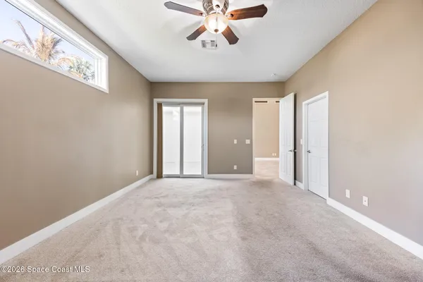 a view of an empty room with window and a ceiling fan