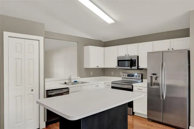 a kitchen with a refrigerator a stove a sink and white cabinets