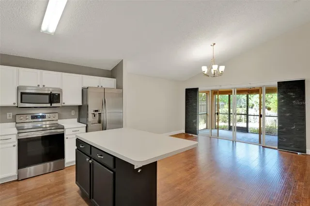 a kitchen with a center island wooden floor and stainless steel appliances