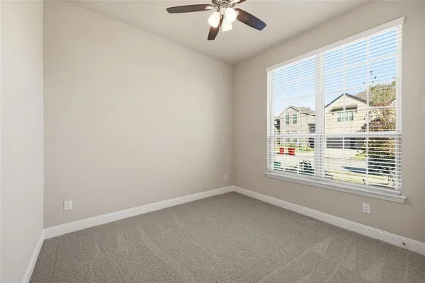 an empty room with windows and chandelier fan
