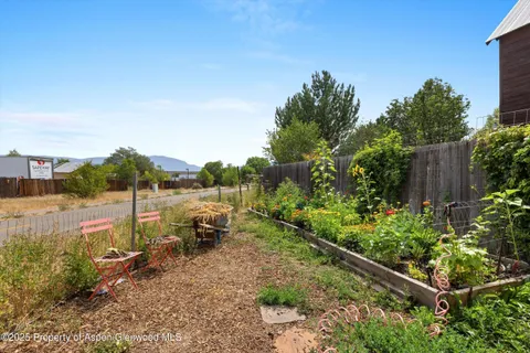 a backyard of a house with table and chairs plants and large trees