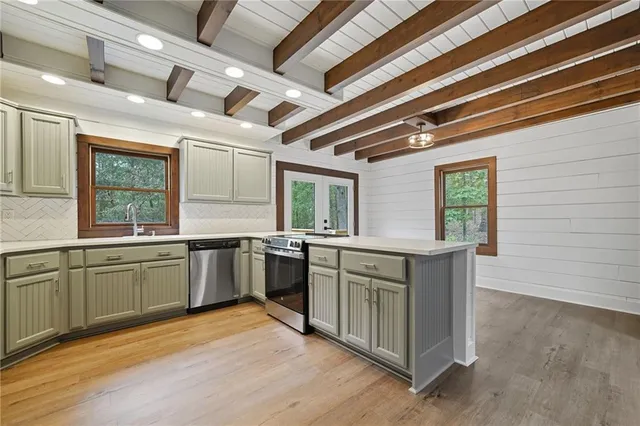 a kitchen with stainless steel appliances granite countertop a sink window and cabinets
