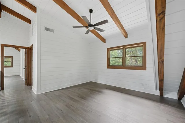 an empty room with wooden floor ceiling fan and windows