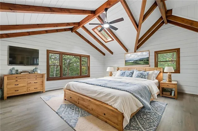 a spacious bedroom with a bed and a flat tv screen