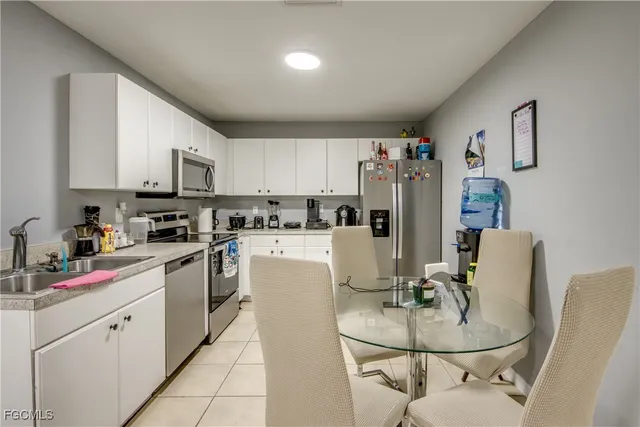 a kitchen with stainless steel appliances kitchen island granite countertop a refrigerator a stove a sink dishwasher and white cabinets with wooden floor