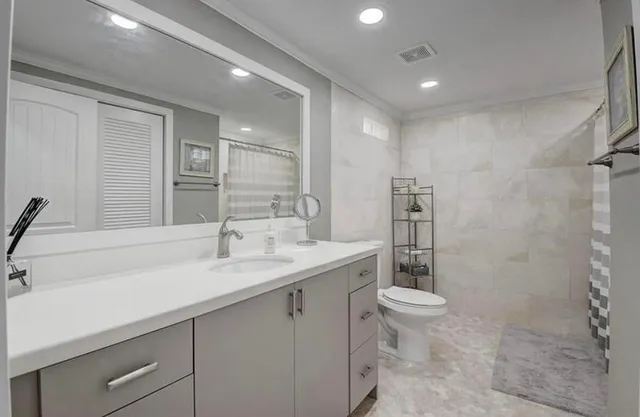 a bathroom with a sink a toilet a mirror and shower