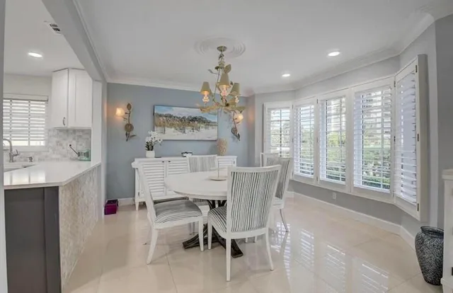 a view of a dining room with furniture a chandelier and a window