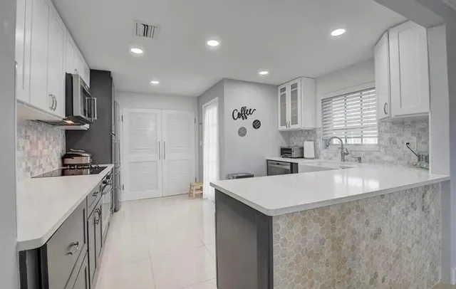 a large kitchen with stainless steel appliances a sink a stove and a refrigerator