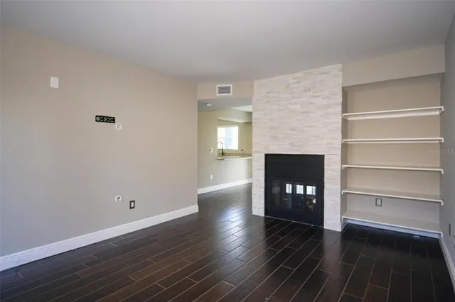 a view of an empty room with wooden floor and a fireplace