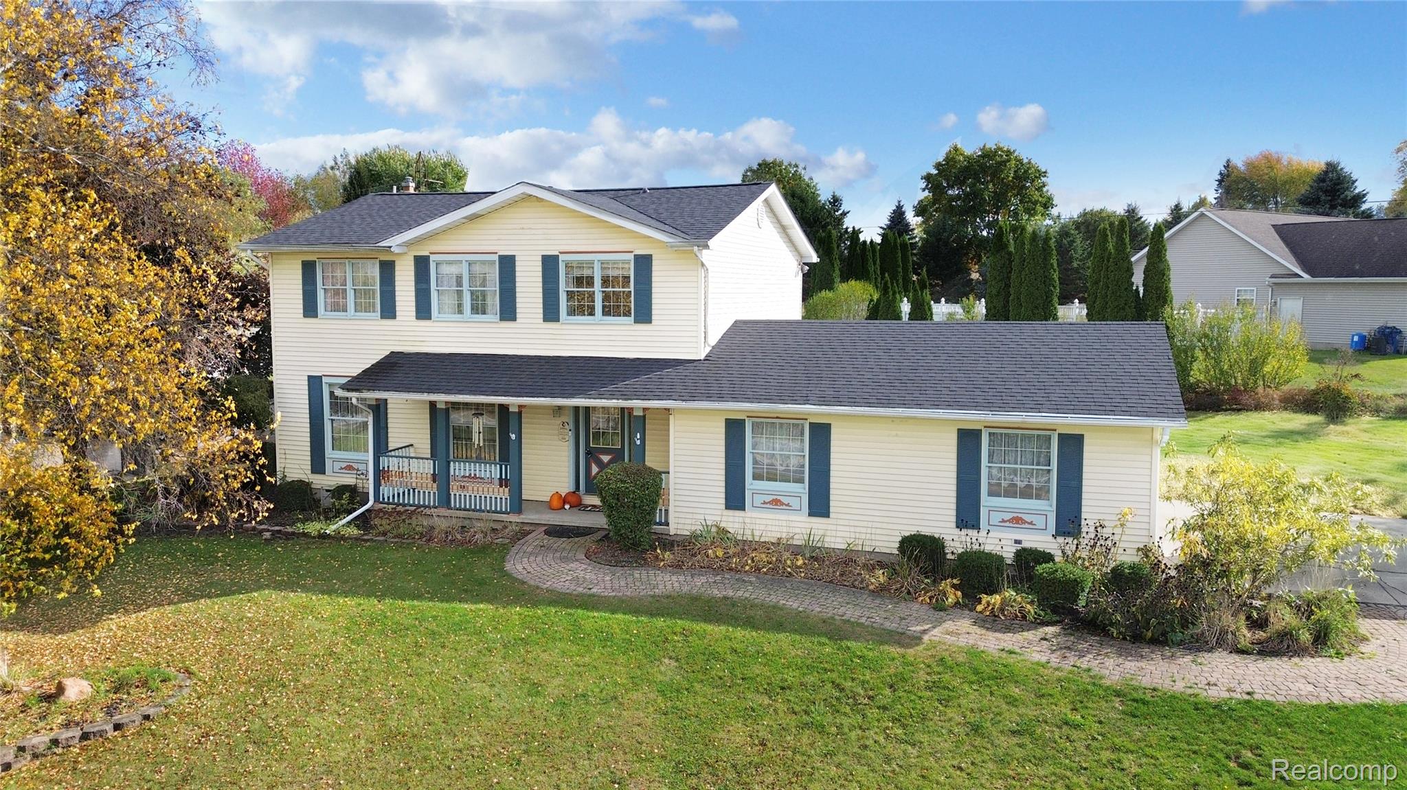 Traditional-style home featuring a porch, a front lawn, and roof with shingles