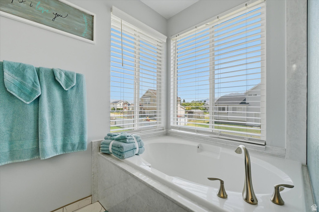 5576 South 4100th Street West Roy, UT 84067 - Photo 22 of 35 Soaking tub surrounded by light-toned tile, featuring brushed nickel fixtures and two large windows with horizontal blinds