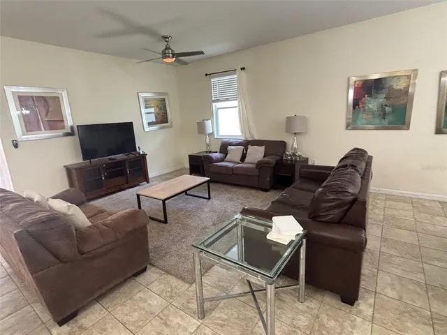 a living room with furniture a flat screen tv and a window