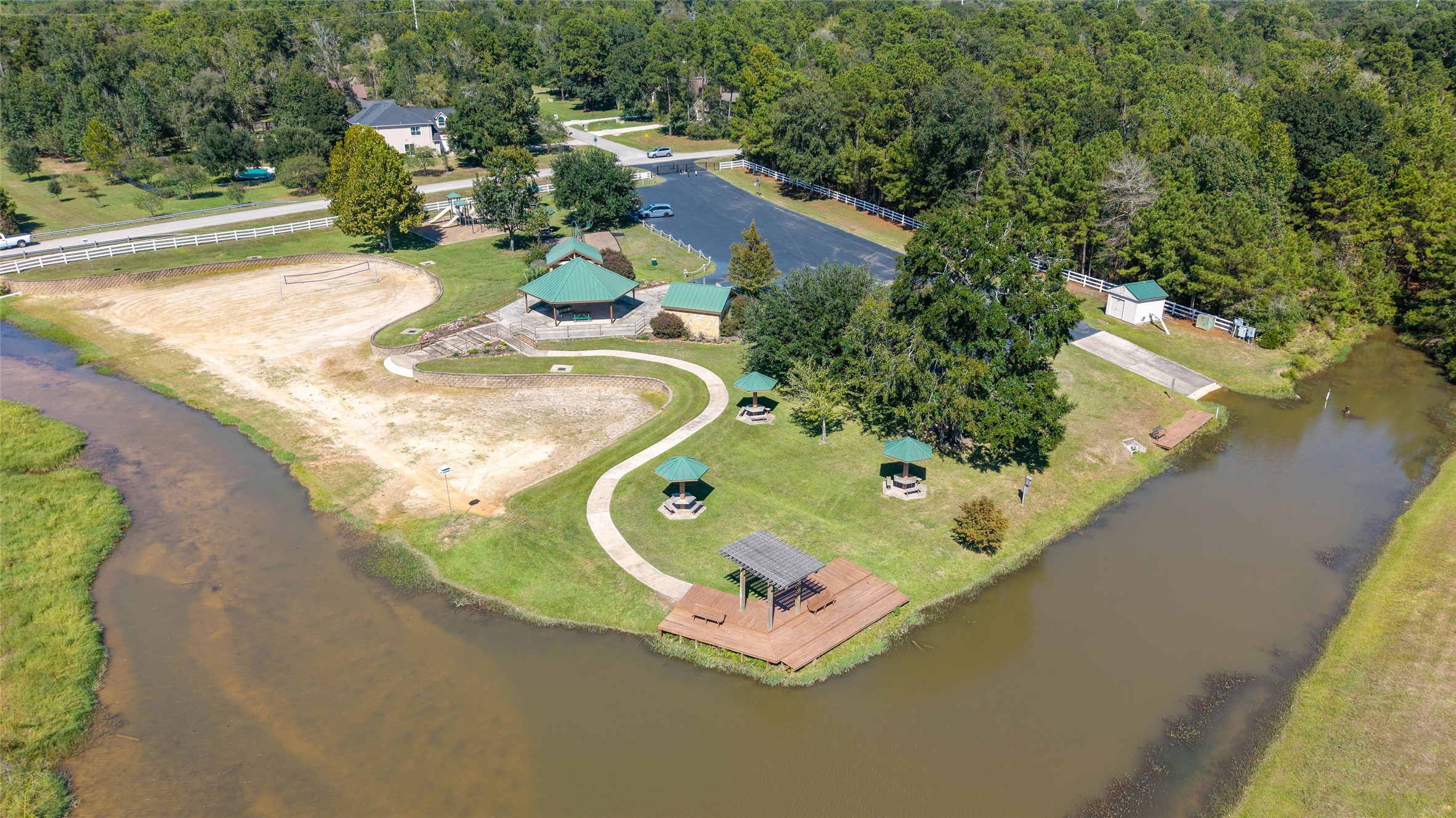 0 Ridgelake Court Montgomery, TX 77316 - Photo 21 of 29 Discover a picturesque lakeside retreat featuring a large covered pavillion, covered picnic tabes, a winding path, and lush greenery, perfect for relaxation and outdoor activities.