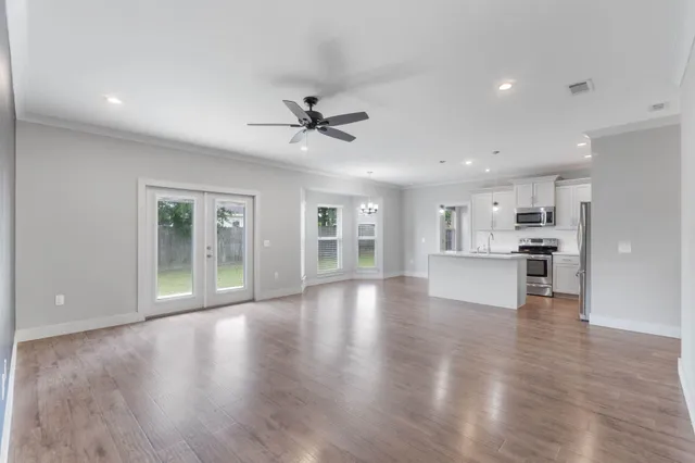 a view of an empty room with wooden floor and a kitchen
